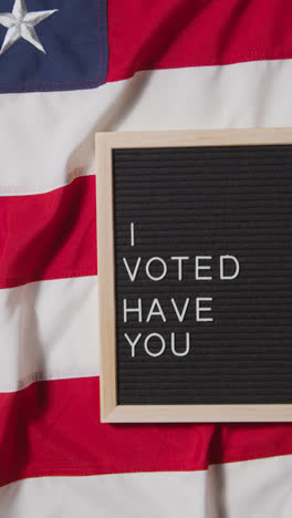 Vertical-Video-Of-Sign-Reading-I-Voted-Have-You-Lying-On-US-Stars-And-Stripes-Flag-For-American-Election-2024-3